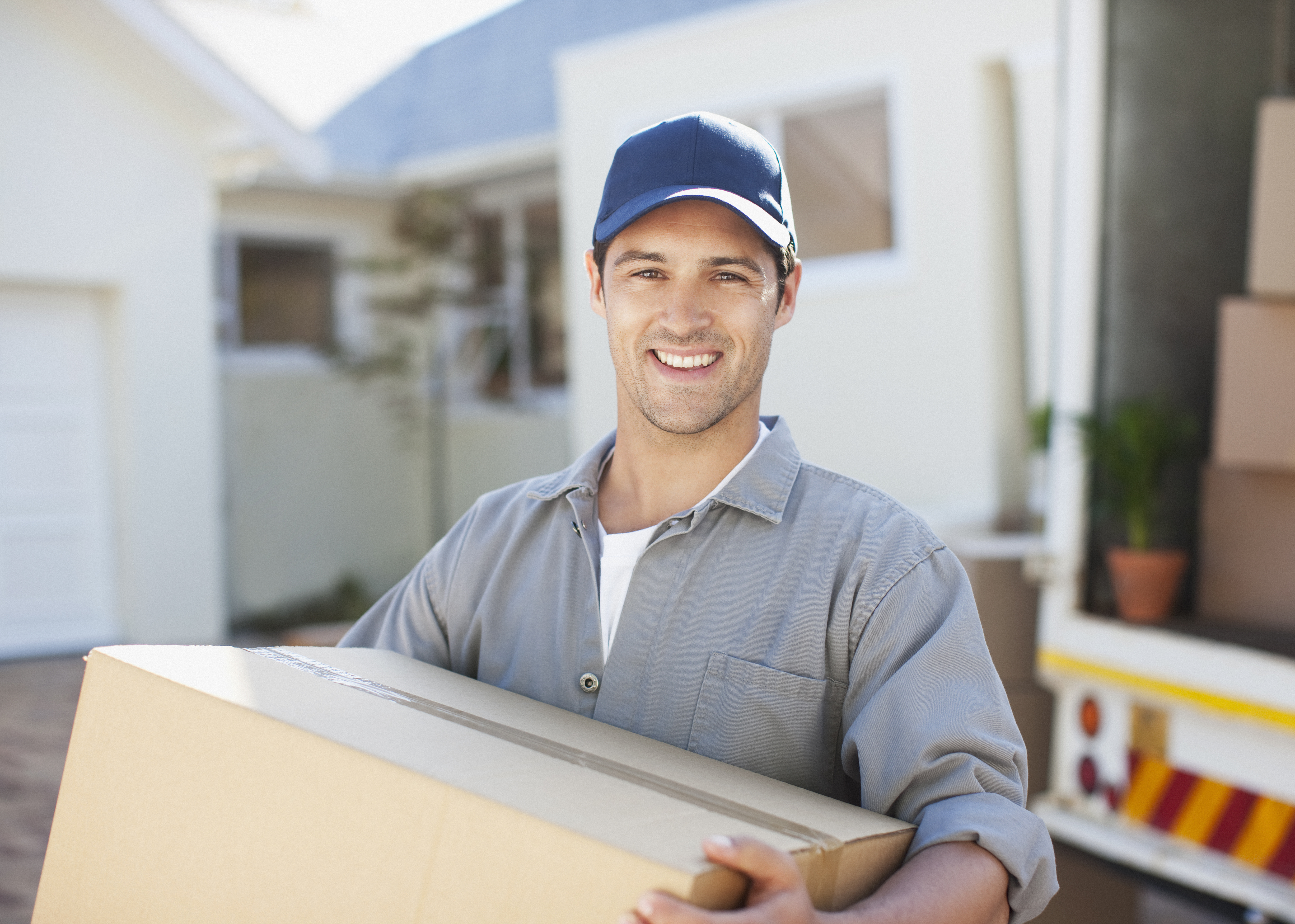 Smiling man carrying box from moving van