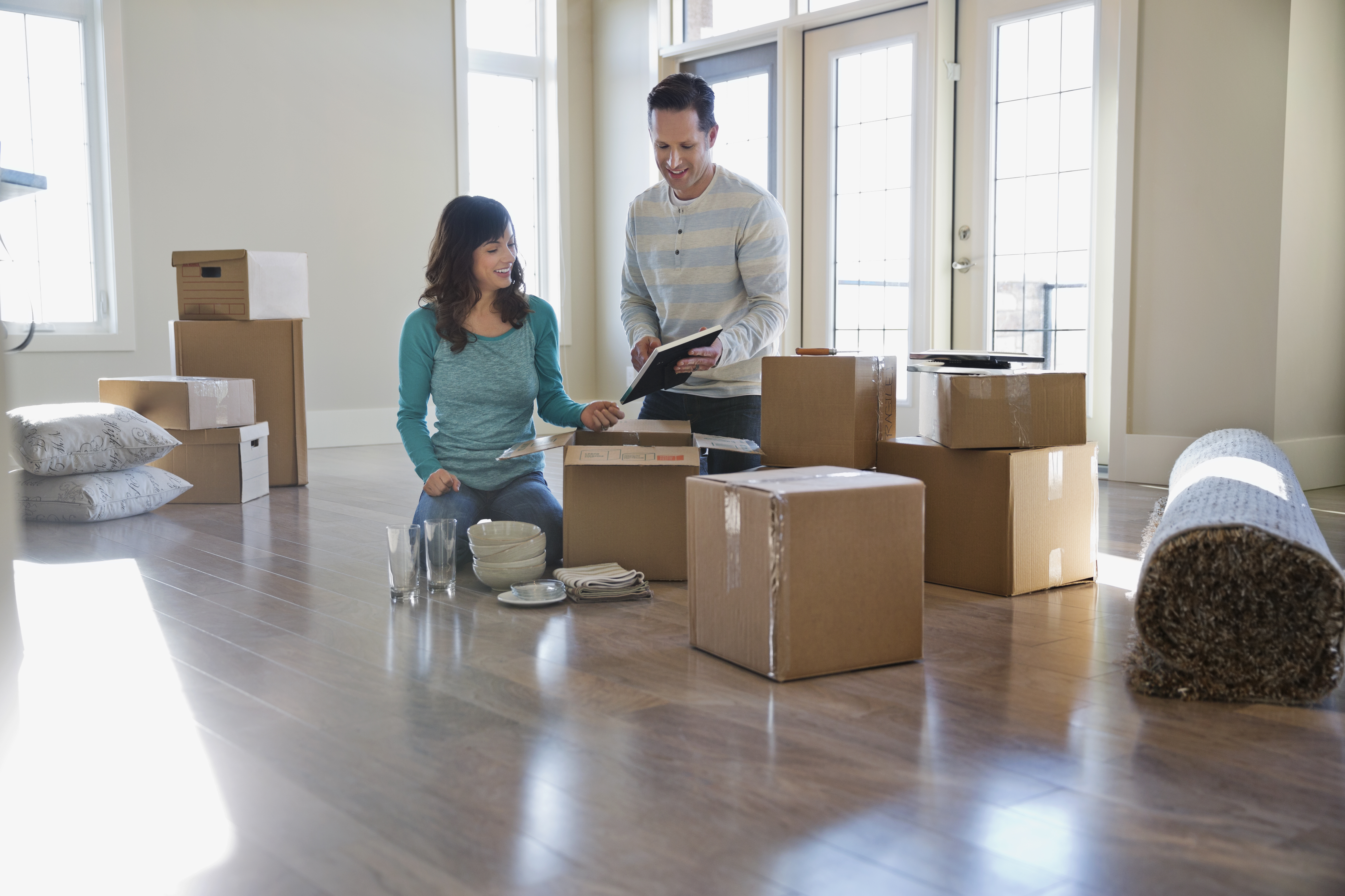 Couple surrounded by cardboard boxes look at moving checklist